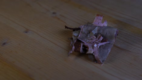 small individual pieces of dry birch bark lie on a wooden table and rotate