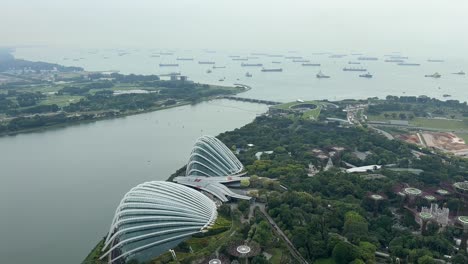 Aerial-view-of-Singapore-from-the-observation-point-atop-Marina-Bay-Sands,-capturing-a-panoramic-vista-of-gardens,-port,-and-serene-waters-with-anchored-vessels