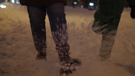 mum and daughter kicking snow on the sidewalk