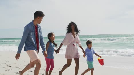 happy hispanic mother, father, son and daughter walking on beach