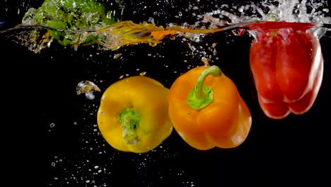 vibrant bell peppers being dropped into water in slow motion