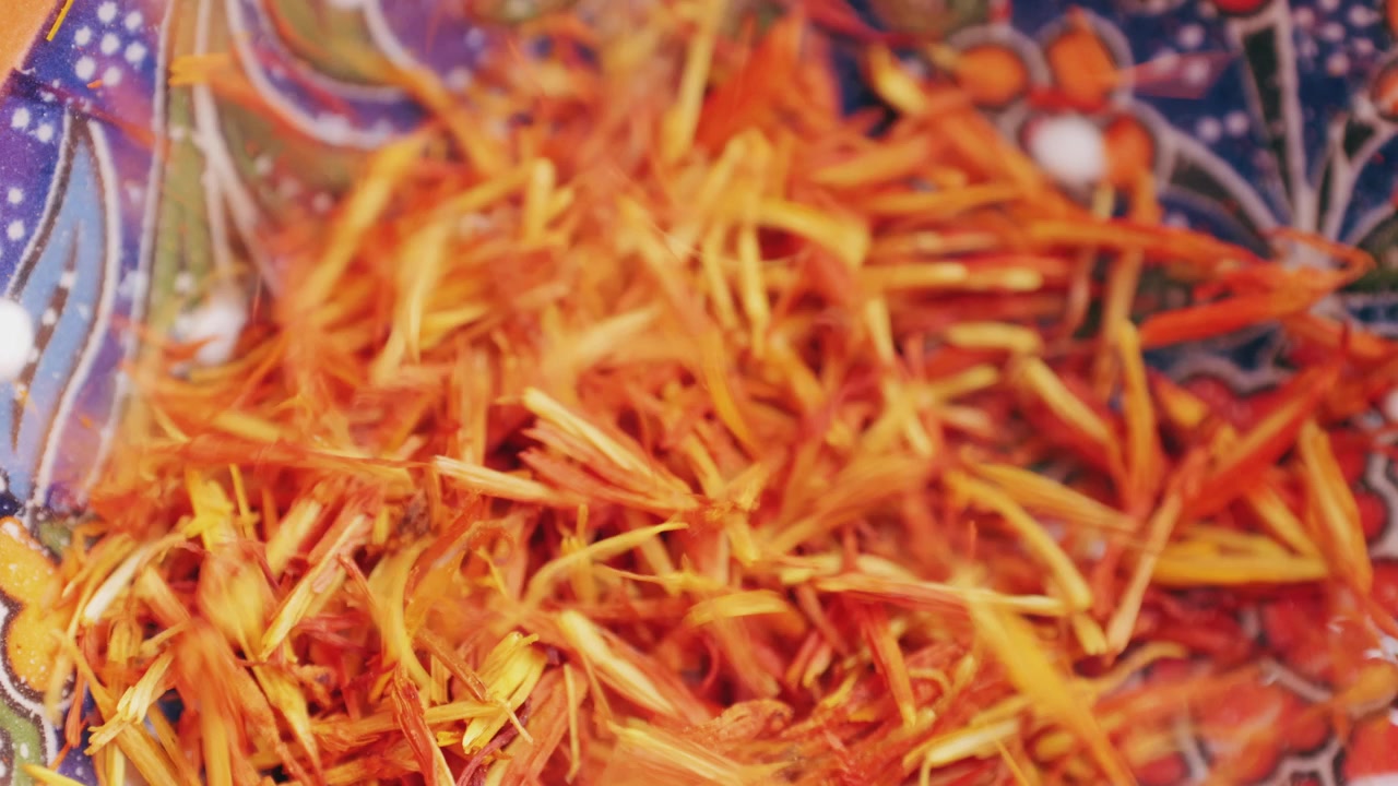 Dried Saffron Threads Pouring into a Traditional Ornate Bowl