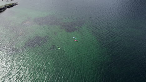 Stand-up-paddling-in-the-scenic-fjord-of-Reinefjorden-in-Lofoten-on-a-nice-summer-day,-circling-shot