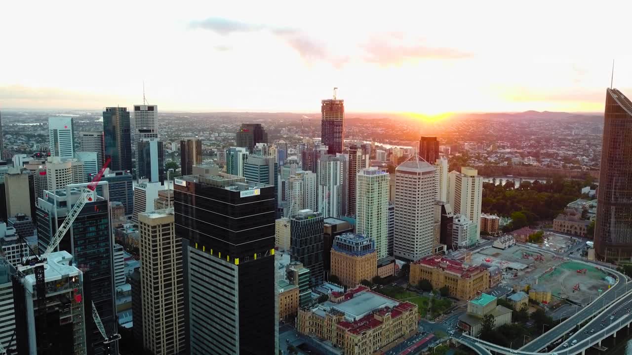 Vista aérea em movimento rápido para trás de um centro da cidade com edifícios altos e tráfego ao nascer do sol