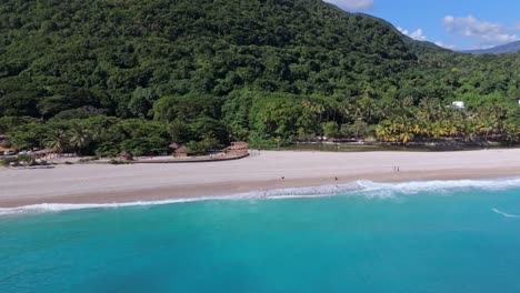 Panorama-Drohnenaufnahme-Eines-Touristen,-Der-Sich-In-Der-Sommersaison-Am-Sandstrand-Vor-Tropischen-Bergen-Entspannt