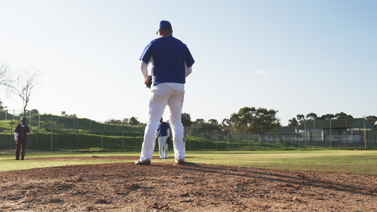 Durante un lancio di baseball, un giocatore in divisa è sul monte di lancio durante la partita, con i compagni di squadra sullo sfondo.