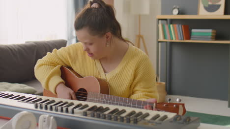 girl with down syndrome playing guitar and singing at home