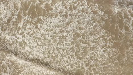 Top-view-of-the-mesmerizing-waves-hitting-the-shore-and-creating-splashes