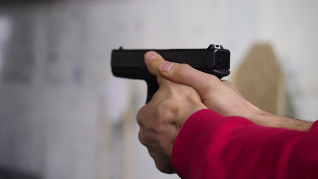 persona que apunta una pistola a un objetivo