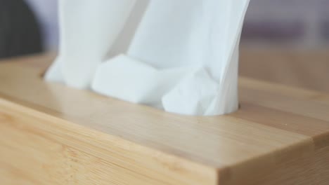 closeup of a hand pulling a tissue from a wooden box