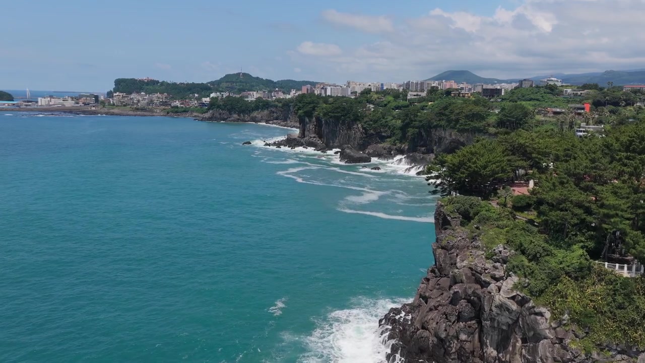 Güney Kore, Jeju Adası, Seogwipo kıyısı boyunca ileri doğru hareket eden yatay kamera çekimi.