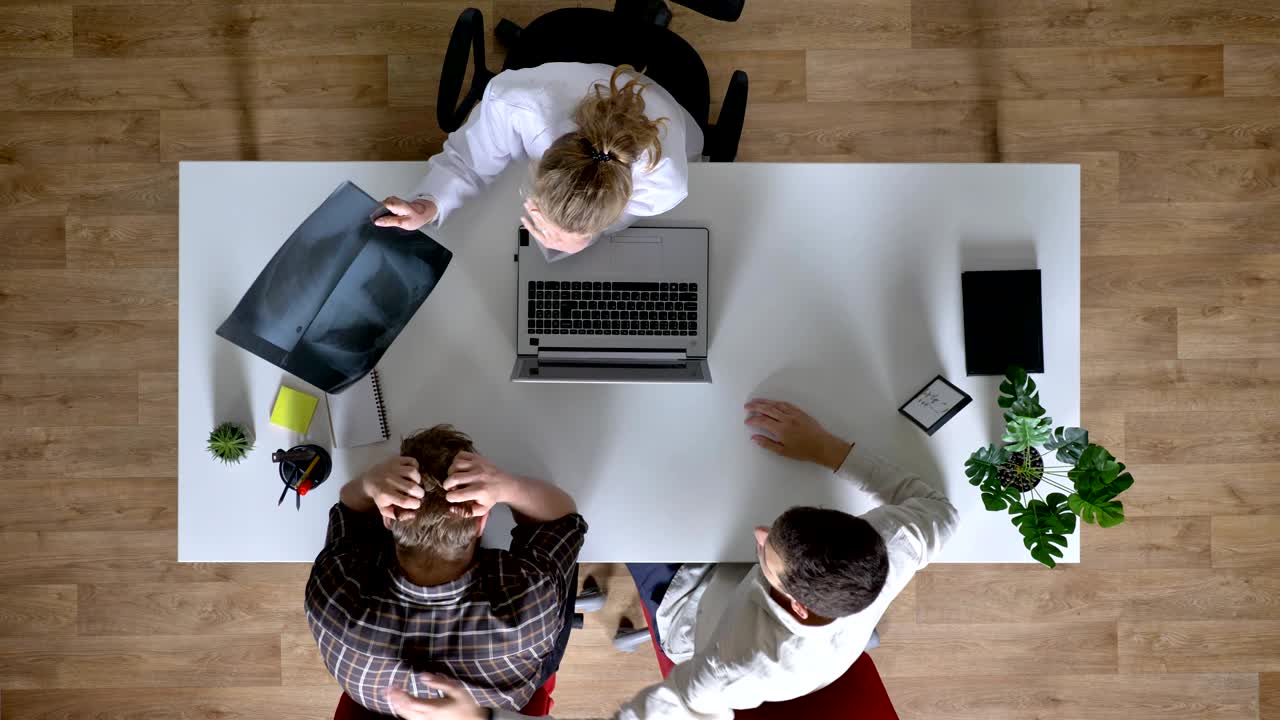 una joven doctora está mostrando escáneres de rayos x a los pacientes y explicando, dos hombres tienen cita con el médico, concepto médico, topshot