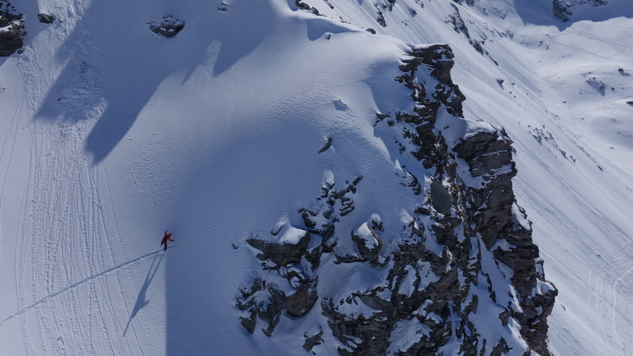 A professional skier hikes up a steep ridge in Verbier, then drops into an epic freeride descent. Pure adventure skiing in deep snow, dramatic terrain, and breathtaking alpine scenery.