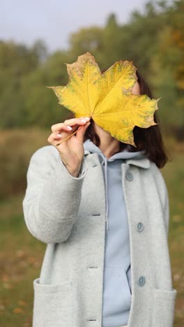 woman holding a yellow autumn leaf