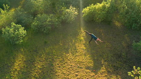 slow motion drone footage of teenage boy doing a forward flip, surrounded by green vegetation