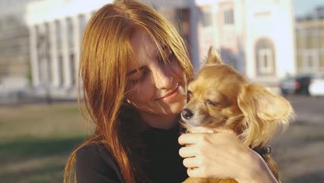 young beautiful woman in the park with her funny long-haired chihuahua dog