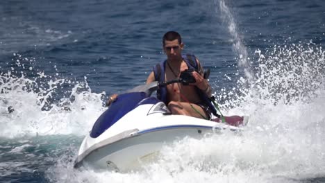 young man riding jetski turning high speed at sea, slow motion panning