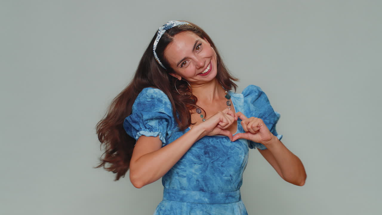 sonriendo encantadora mujer joven hace el gesto del corazón demuestra el amor señal expresa buenos sentimientos