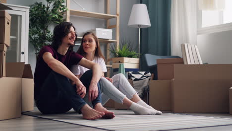 couple sitting in their new home surrounded by moving boxes