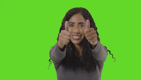 studio portrait shot of woman giving double thumbs up sign against green screen 2