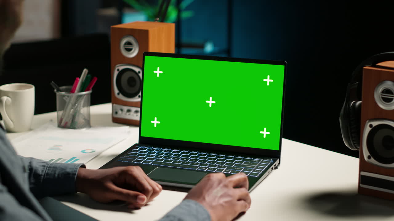 hombre afroamericano trabajando desde casa con pantalla verde en la computadora portátil
