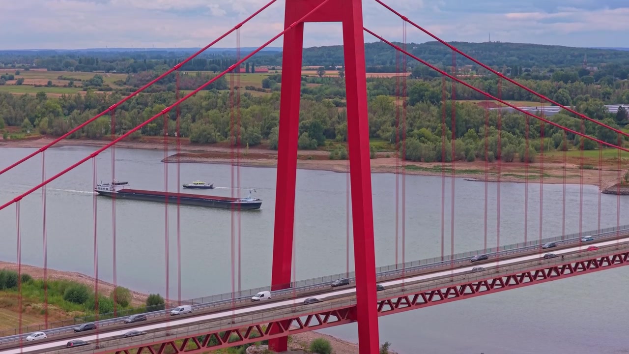 Vista aérea del tráfico en un puente colgante rojo sobre un río