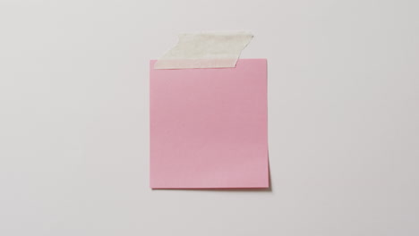 video de primer plano de una nota de nota rosa con espacio de copia pegado a un fondo blanco