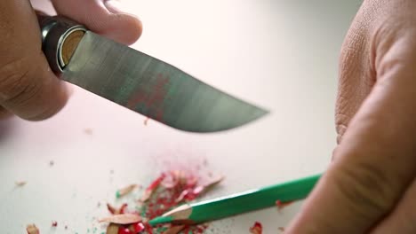 imágenes de manos afilando lentamente un lápiz y algunos lápices de colores con un cuchillo afilado