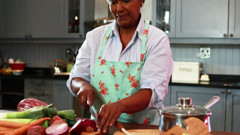 Senior-woman-chopping-vegetables-in-kitchen