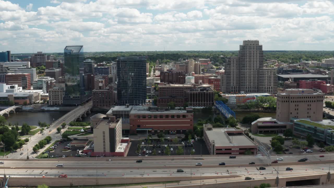 Video de dron en plano general del horizonte de Grand Rapids, Míchigan, sobre la autopista, descendiendo.