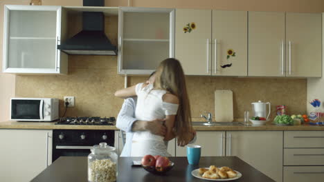 una pareja besándose en la cocina.