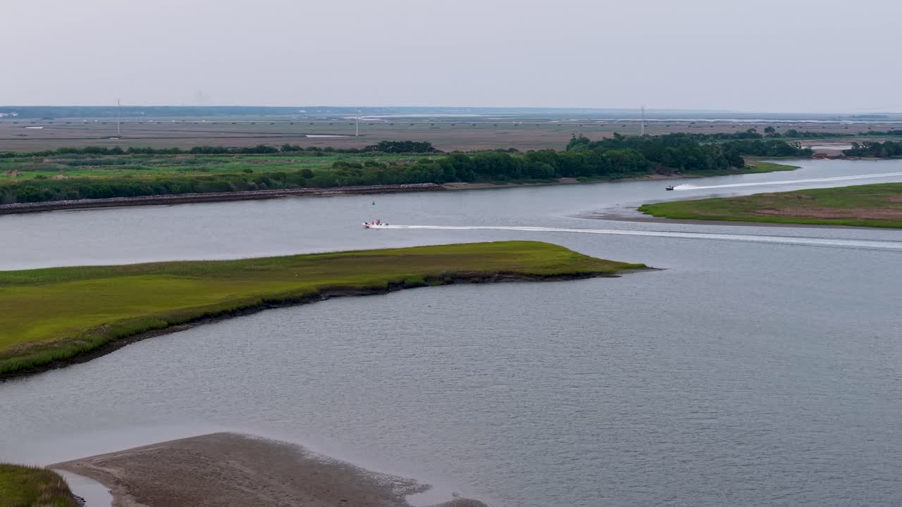 Vista aerea da drone di un fiume tortuoso che taglia una verde zona paludosa vicino a Charleston, nella Carolina del Sud, mentre una barca percorre il corso d'acqua sotto un cielo azzurro. Tranquillo paesaggio lowcountry.