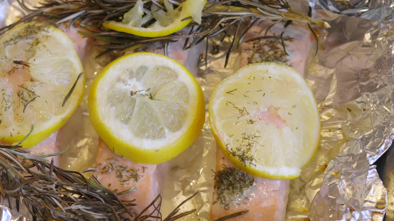 Vista dall'alto di salmone al forno condito con limone, rosmarino e aneto. Cena sana a base di pesce ricca di Omega-3 e ad alto contenuto proteico. Cucina casalinga. 4K