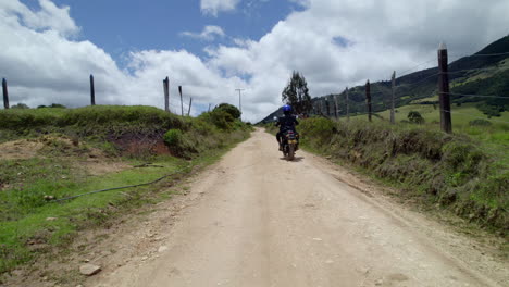 aerial view of man riding a motorcycle through picturesque countryside landscapes. some clouds in background in sunny day
