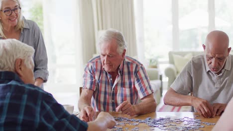 Diverse-group-of-senior-male-and-female-friends-doing-jigsaw-puzzle-in-living-room,-slow-motion