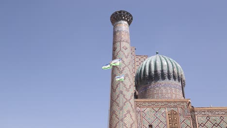 uzbek flags waving in front of registan square in samarkand, uzbekistan along the historic silk road