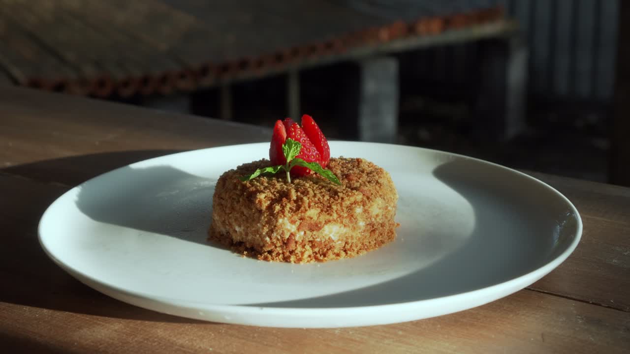 un pequeño pastel de napoleón con fresas en la parte superior de pie en un plato blanco