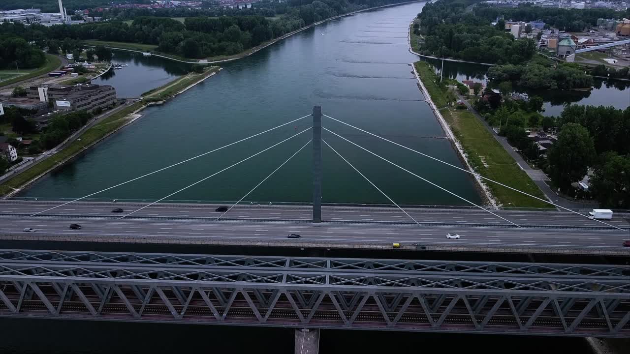 Timelapse footage of a bridge across a river with lots of traffic passing by while drone flies high above in Europe at sunset