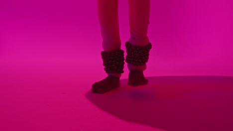 cerca de los pies y las campanas de la bailarina de kathak femenina que realiza el baile vestida con el vestido tradicional indio contra un fondo púrpura 2