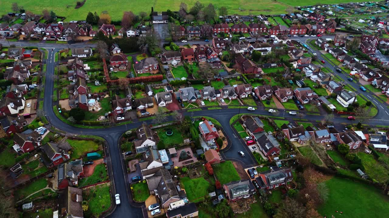 En panoramisk droneoptagelse fra luften over forstæderne til Southampton, med Botley landsbys boliger ved solnedgang på en overskyet vinterdag, med biler der passerer forbi på vejene nedenfor, forbi den lille bebyggelse i byen.