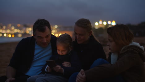 family watching screen on ocean beach
