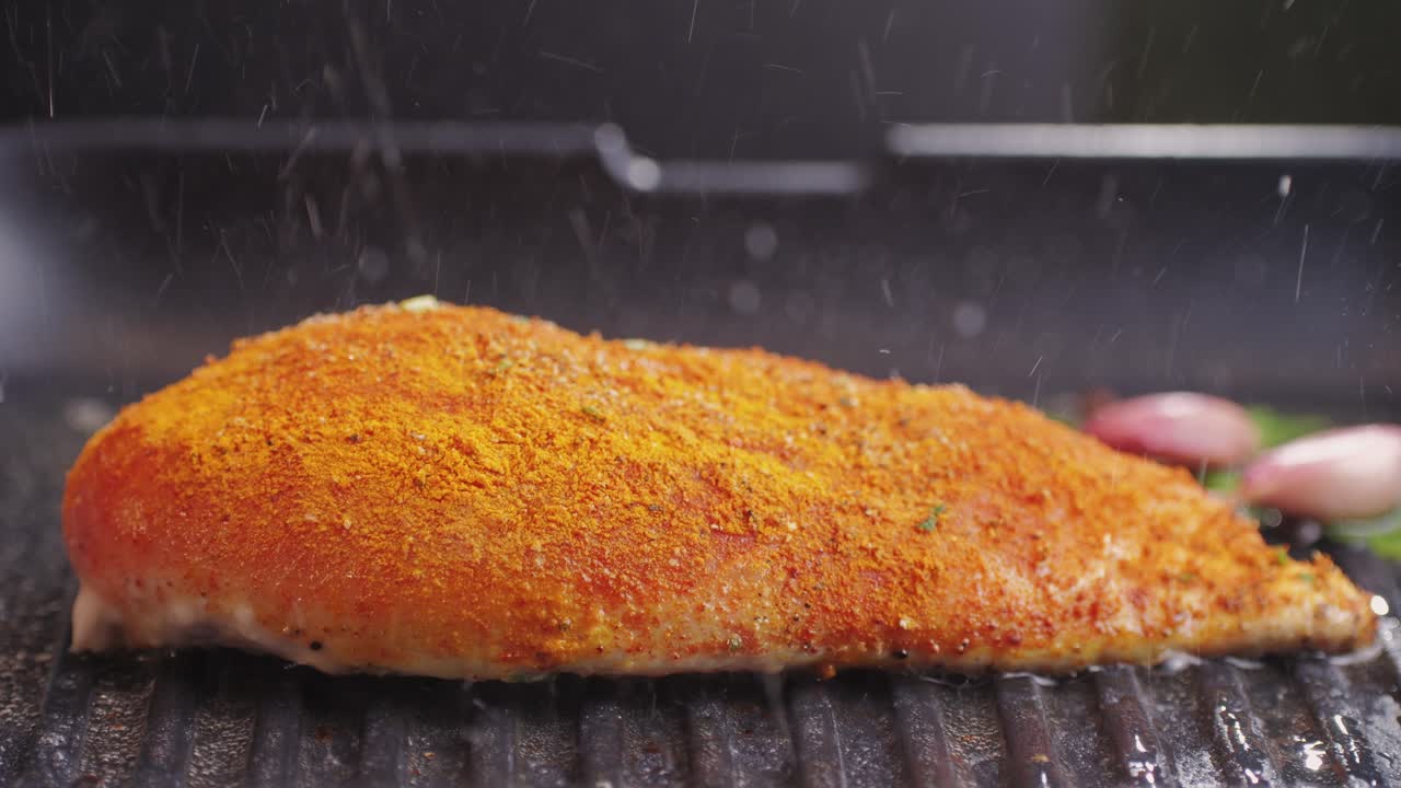 Cooking raw chicken meat in yellow turmeric spice with garlic and greens on grill close-up. Preparing raw food for cooking. Grilled chicken, duck, turkey kebab with vegetables.