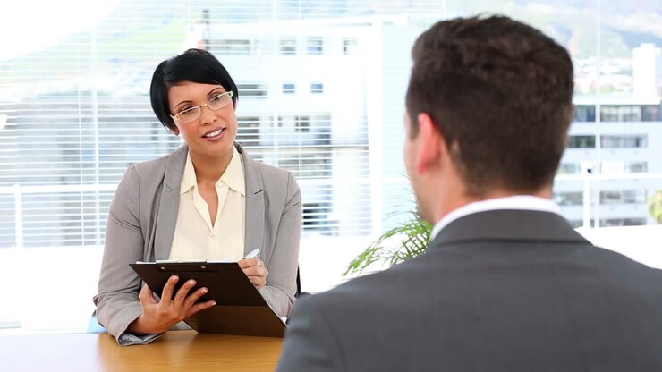 Businesswoman interviewing man at her desk