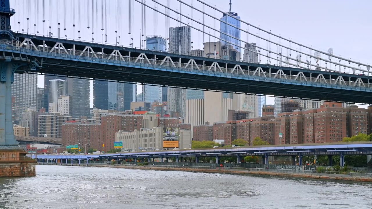 New York, USA, 8. mai 2026: Manhattan Bridge strekker seg over East River med midtown skyline, New York. Blå stålfagverk, mursteinsbygninger og disig dagsatmosfære