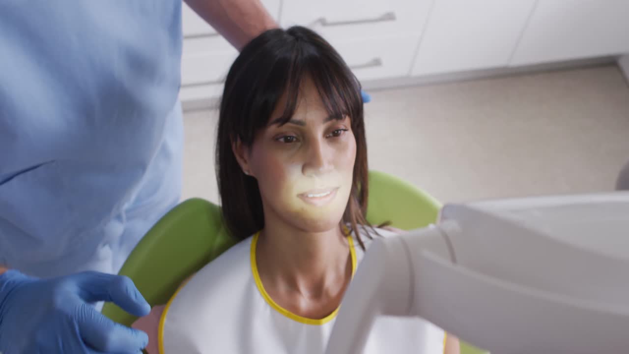 dentista caucásico preparando a una paciente en una silla en una clínica dental moderna
