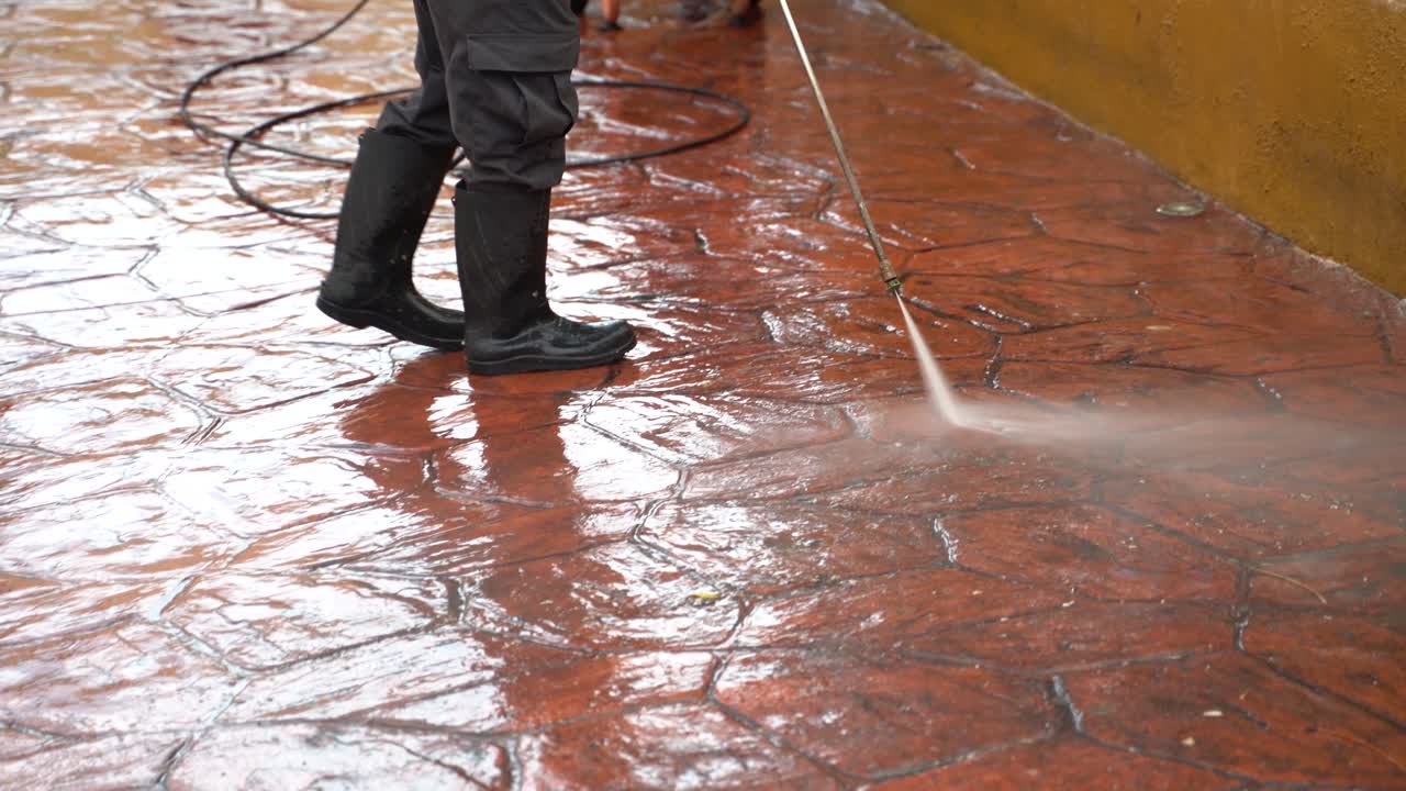 Closeup on waist down shot of person power washing the sidewalk in a park
