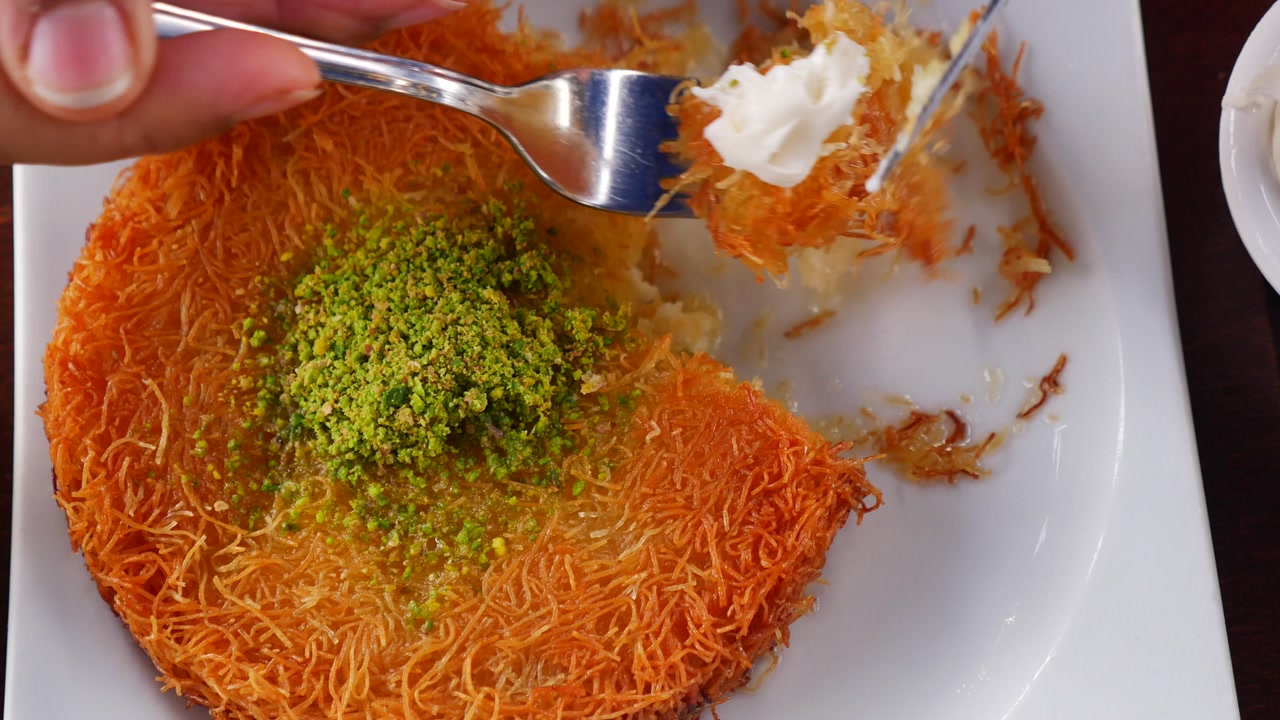 Serving a Slice of Traditional Turkish Kunefe Dessert with Pistachio and Cream