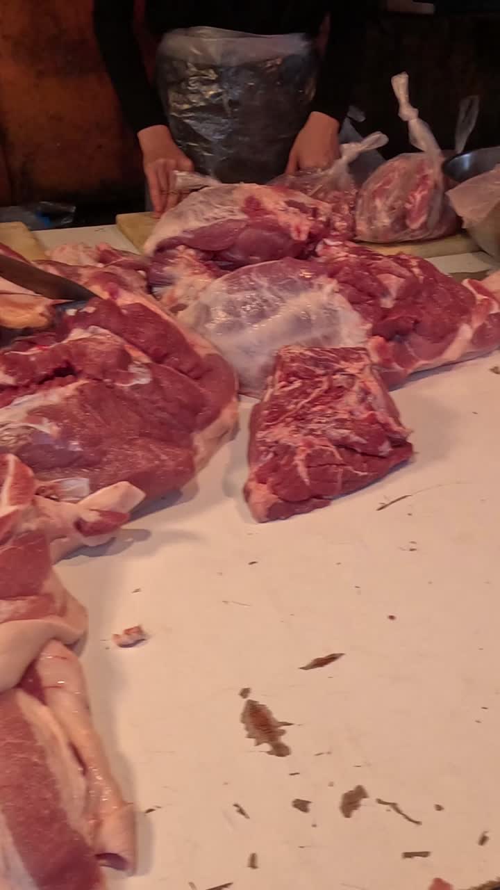 Tukang daging memotong dan menata daging di konter.