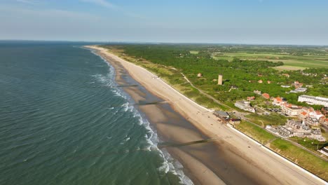 Beautiful-aerial-shot-of-the-beach-of-a-small-coastal-town-in-a-rural-area-on-a-cloudless-summer-evening
