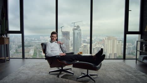 businessman relaxing in office chair. exhausted employee adjusting tie in office